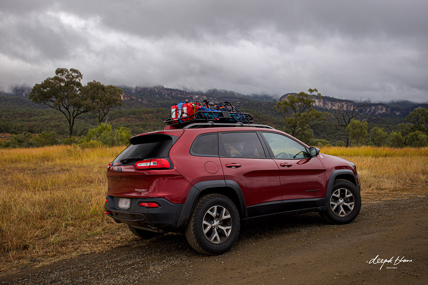 Carnarvon Gorge - Jeep with roof rack on dirt road with cliffs in the background